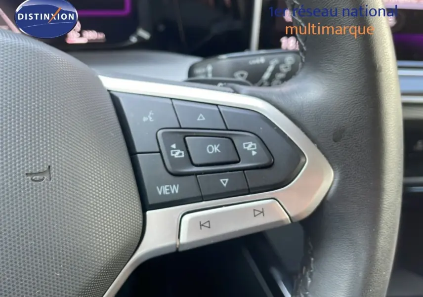 Gros plan sur les commandes gauche du volant en cuir noir de la Volkswagen Golf SW gris lunaire 2024.