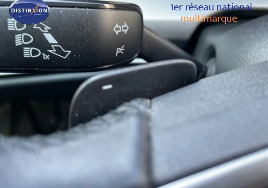 Gros plan sur la commande de clignotants et volant en cuir gris dans l'habitacle d'une Volkswagen Golf SW 2024 gris lunaire.