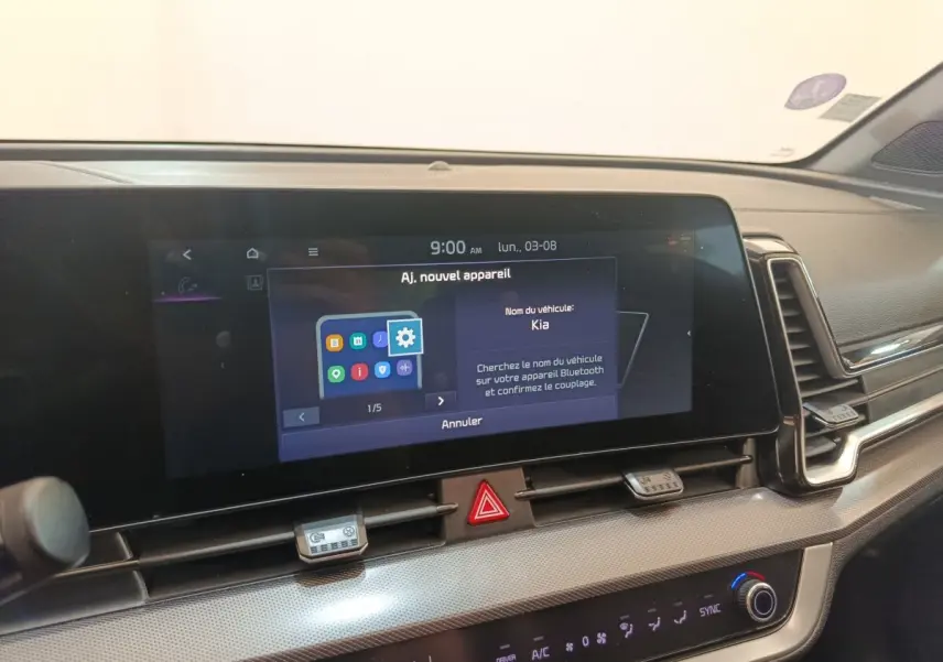 Vue intérieure du tableau de bord du Kia Sportage gris clair 2022, avec écran tactile central allumé affichant le Bluetooth.