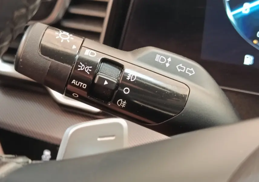 Gros plan sur la commande des feux et clignotants du volant d’un KIA Sportage gris clair 2022, intérieur moderne.
