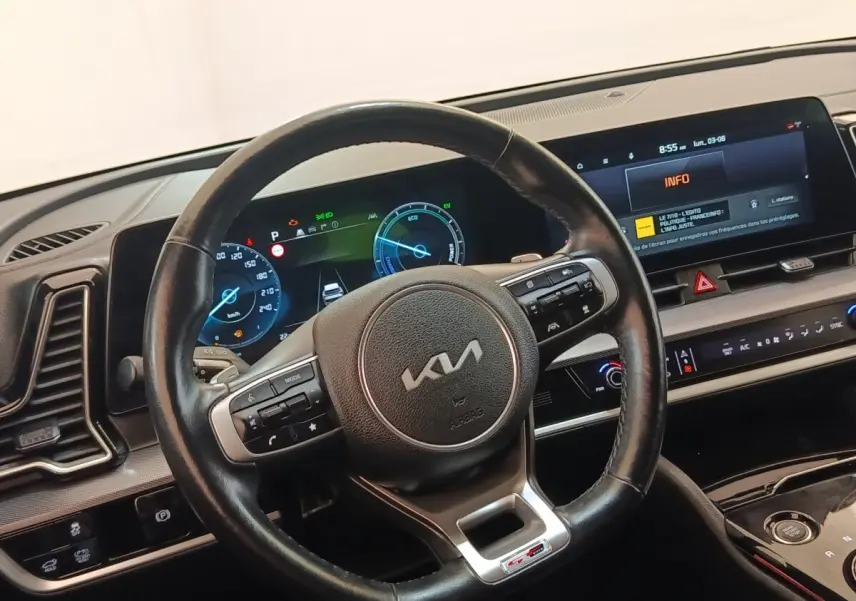 Vue intérieure centrée sur le volant cuir KIA GT-Line avec tableau de bord digital et écran tactile 12,3 pouces.