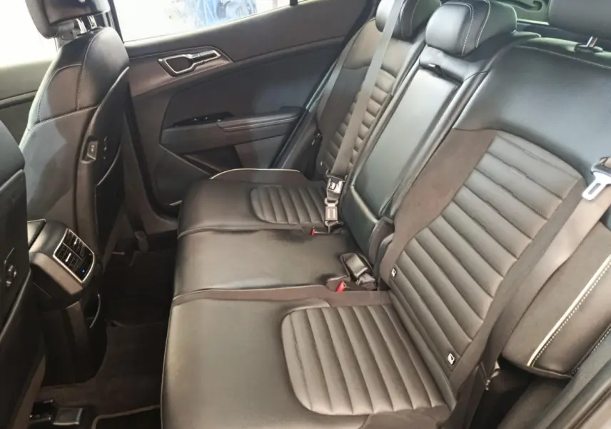 Vue latérale intérieure sur la banquette arrière en cuir noir du Kia Sportage 2022 avec ceintures de sécurité visibles.