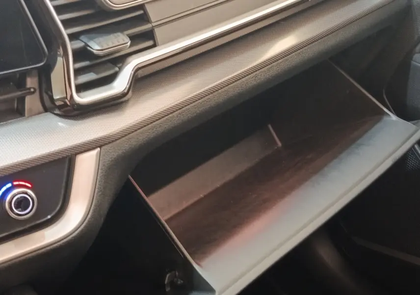 Gros plan sur la boîte à gants ouverte et le tableau de bord gris clair du Kia Sportage 2022 côté passager.