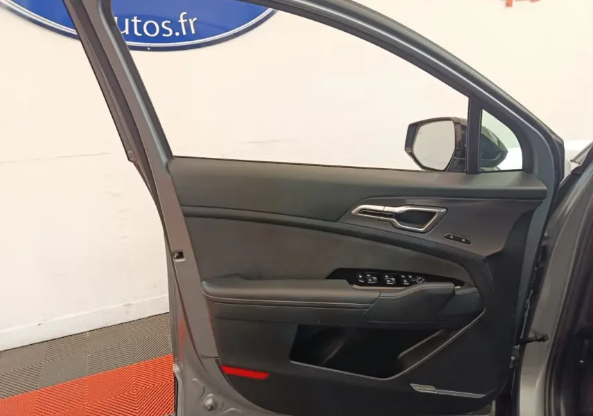 Vue intérieure de la porte avant gauche gris clair du Kia Sportage 2022 avec commandes électriques et insert décoratif noir.