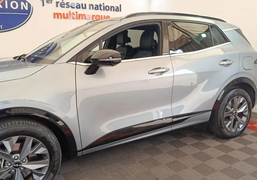 Vue de profil côté gauche du Kia Sportage gris clair 2022 avec jantes alliage et rétroviseurs électriques rabattables.