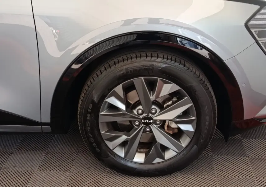 Gros plan sur la roue arrière droite gris clair du Kia Sportage 2022 avec jante alliage et logo Kia central.