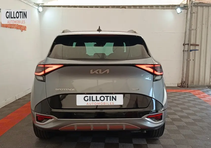 Vue arrière d'un KIA Sportage gris clair 2022 avec feux LED allumés et logo GT-LINE PREMIUM visible.