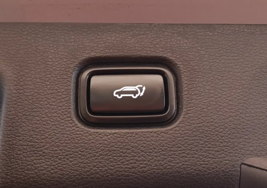 Bouton noir d'ouverture électrique du coffre sur panneau intérieur texturé du Kia Sportage gris clair 2022.