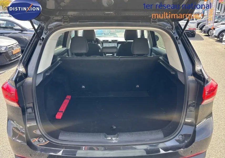 Coffre ouvert vu de l'arrière d'un MG MOTOR ZS 1.5L HYBRID+ 197CH LUXURY noir Pebble Black Metal, intérieur spacieux avec triangle de sécurité rouge.