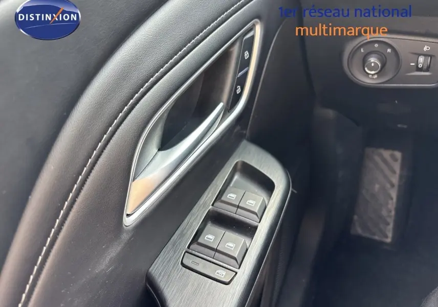 Gros plan sur la commande des vitres côté conducteur en finition noire, avec poignée argentée du MG ZS 2025 Pebble Black.
