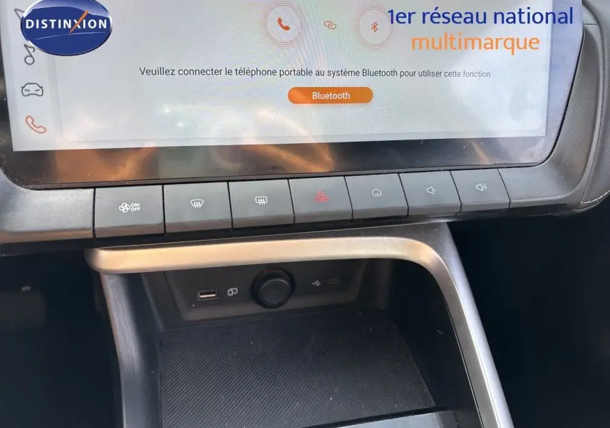 Gros plan sur la console centrale du MG ZS 1.5L HYBRID+ 197CH Luxury 2025, écran tactile et commandes climatisation visibles.