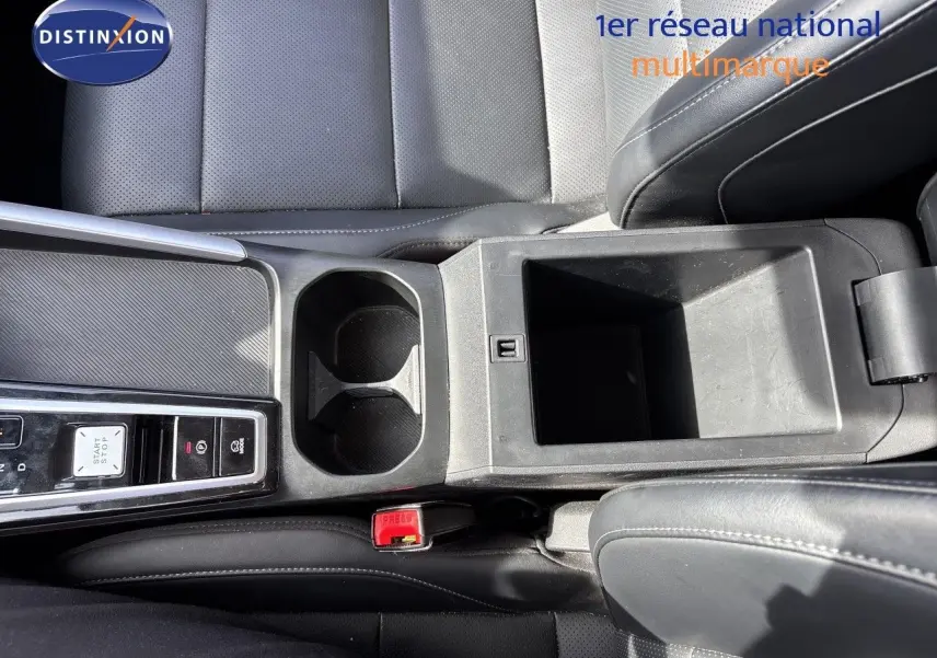 Vue plongeante sur la console centrale noire du MG MOTOR ZS 1.5L HYBRID+ 197CH LUXURY avec porte-gobelets et rangement ouvert.
