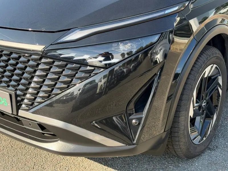Gros plan sur l'avant droit noir Kuro métallisé du Nissan Qashqai 2025 avec phares LED et jante alu distinctive.