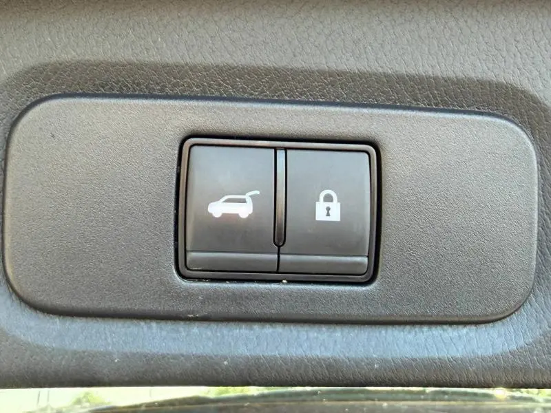 Boutons noirs de commande d'ouverture de coffre et de verrouillage, vue rapprochée à l'intérieur du Nissan Qashqai 2025.