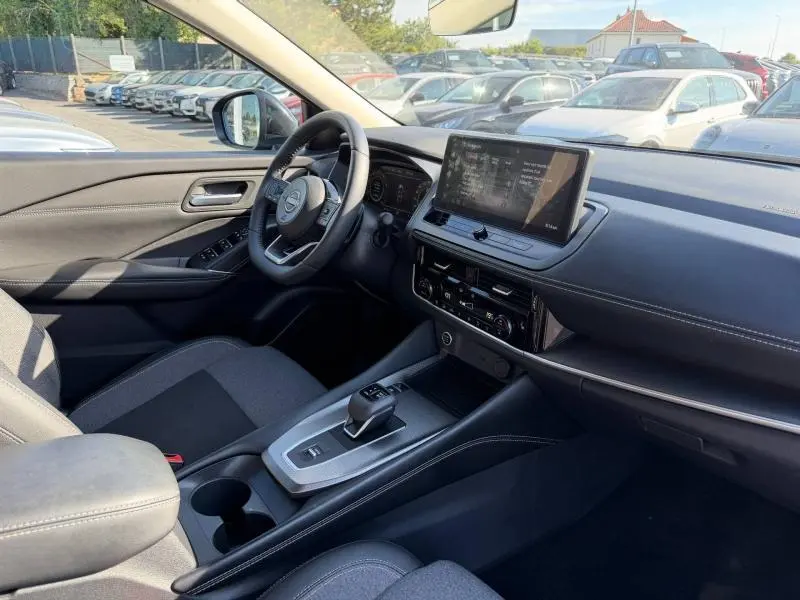 Vue intérieure côté conducteur du Nissan Qashqai 2025 noir Kuro, avec tableau de bord moderne et écran tactile central.