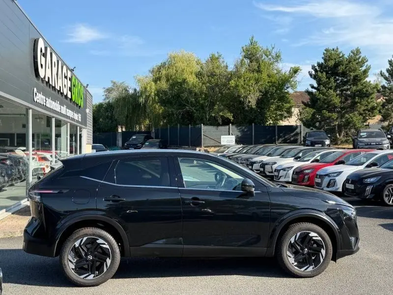 Vue de profil côté gauche du Nissan Qashqai 2025 noir Kuro métallisé avec jantes alliage distinctives, stationné en extérieur.