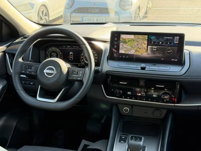 Vue intérieure du tableau de bord du Nissan Qashqai 2025, avec volant cuir multifonction et écran tactile central affichant la navigation.