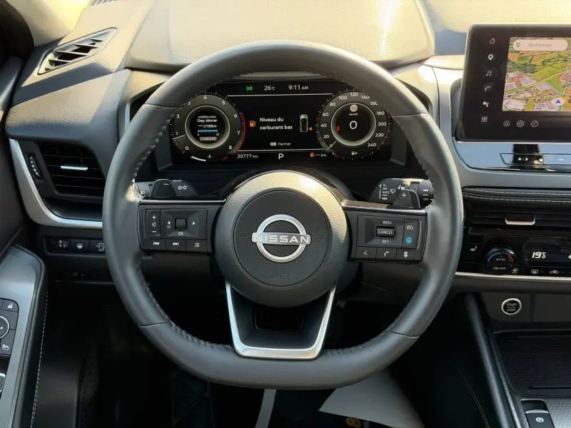 Vue intérieure centrée sur le volant cuir multifonction du Nissan Qashqai 2025 avec tableau de bord numérique et écran tactile.