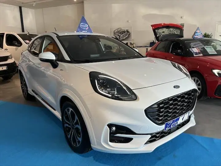 Ford Puma blanc glacier vu en 3/4 avant droit dans un showroom avec calandre noire et jantes alliage.