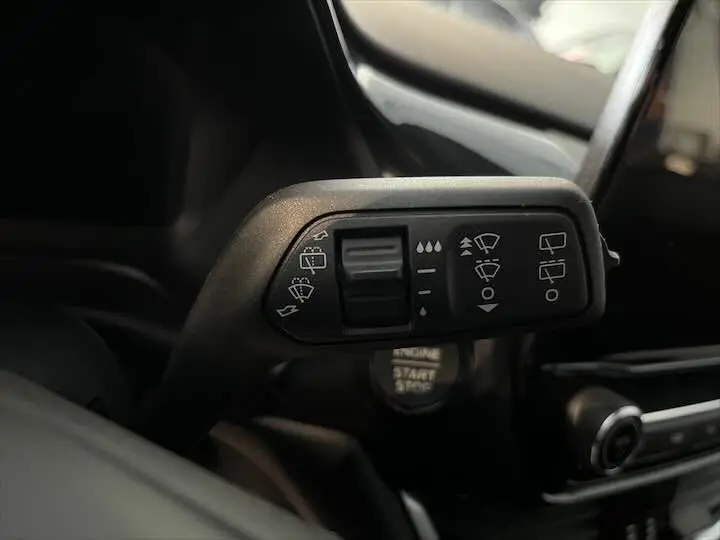 Gros plan sur la commande des essuie-glaces dans l'habitacle sombre d'une Ford Puma blanc glacier 2022.
