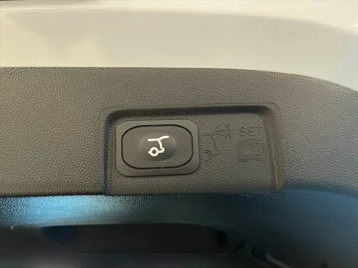 Bouton de commande du hayon électrique sur la partie intérieure arrière d'un Ford Puma blanc glacier.