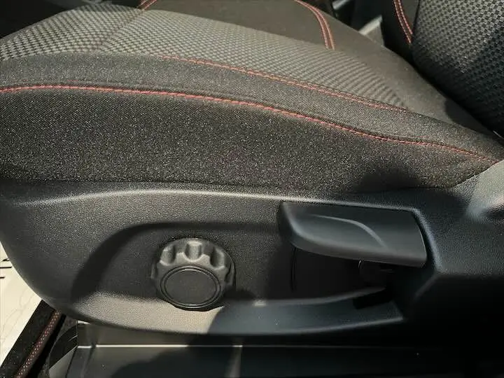 Réglage manuel du siège avant avec tissu noir et surpiqûres rouges dans une Ford Puma blanc glacier 2022.