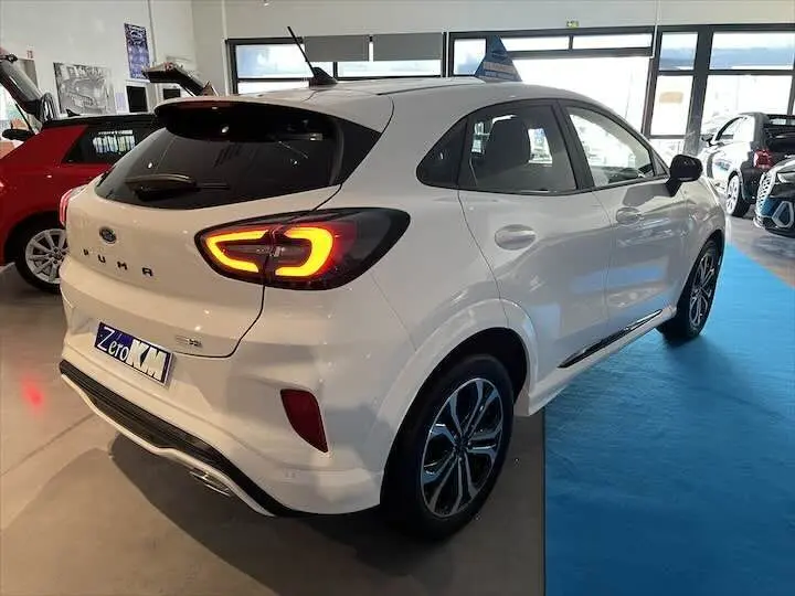 Vue 3/4 arrière droite d'une Ford Puma blanc glacier avec feux arrière allumés en concession.