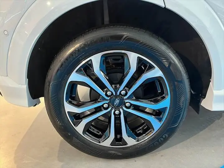Gros plan sur la roue avant droite d'un Ford Puma blanc glacier avec jante alliage noire et argentée.