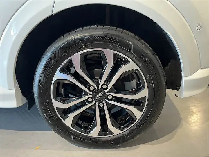 Gros plan sur la roue avant droite d’un Ford Puma blanc glacier avec jante alliage noir et argentée.
