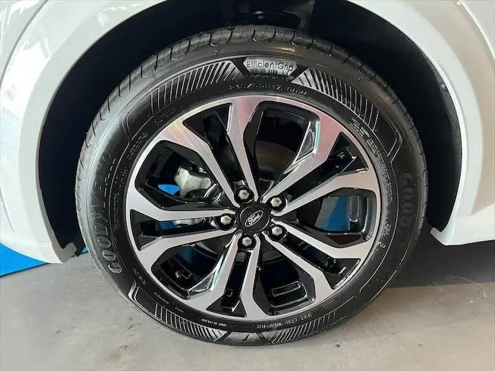 Gros plan sur la roue avant droite d'une Ford Puma blanc glacier avec jante alliage noire et argentée design moderne.
