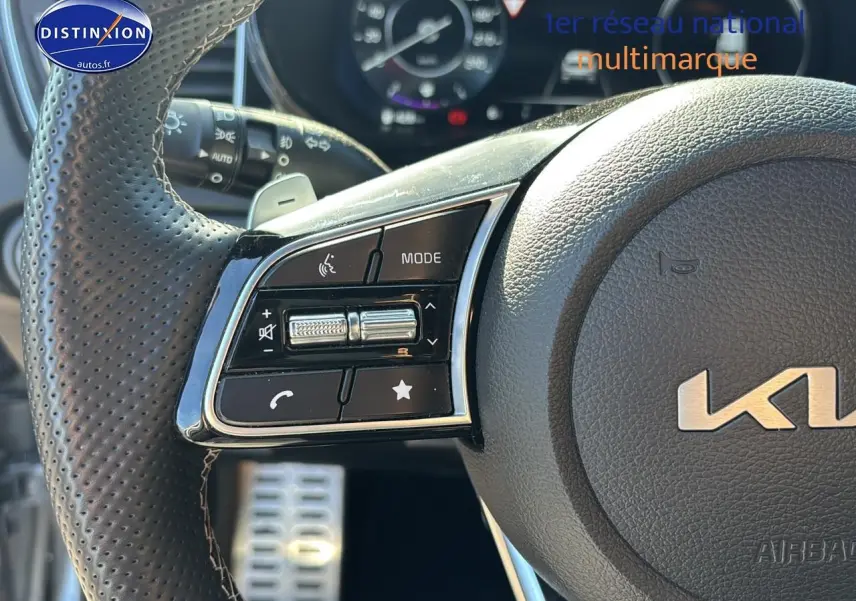 Gros plan sur le volant cuir perforé de la KIA Xceed 2024 avec commandes multifonctions et palettes au volant.