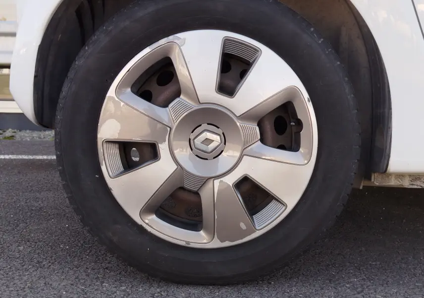 Gros plan sur la roue avant droite d'une Renault Twingo Blanc Cristal, avec jante en alliage argentée marquée du logo Renault.