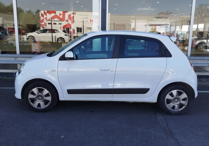Profil côté gauche d'une Renault Twingo 1.0 SCe 70ch Zen blanche, avec baguettes latérales noires et jantes d'origine.