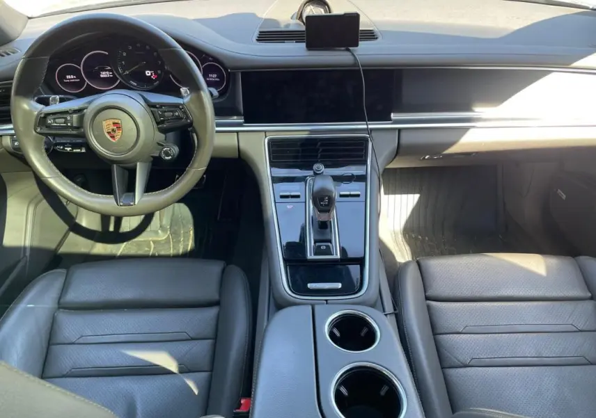 Vue intérieure du tableau de bord et console centrale du Porsche Panamera gris, avec volant multifonctions et écran tactile éteint.