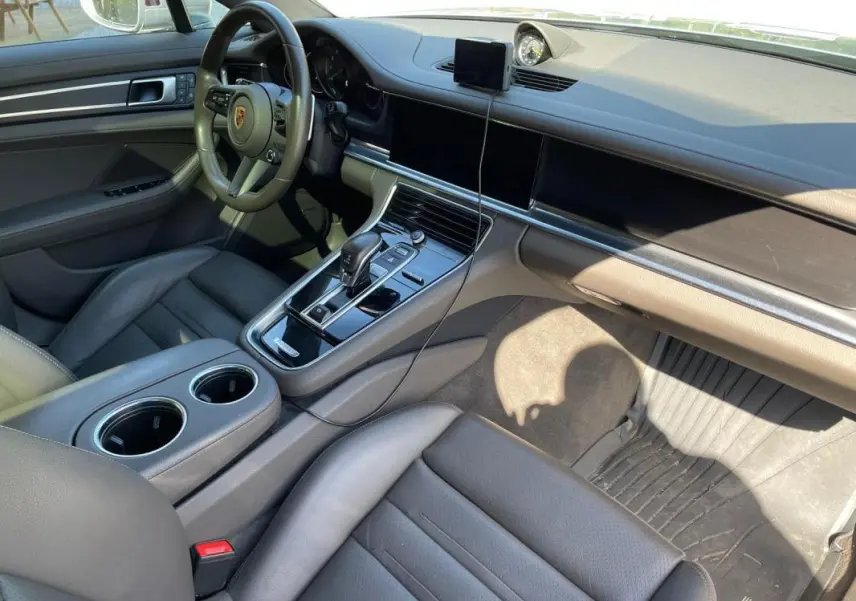 Vue intérieure côté conducteur du Porsche Panamera gris, mettant en valeur le tableau de bord moderne et la console centrale.