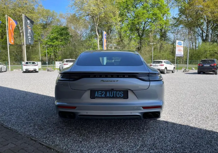 Vue arrière d'une Porsche Panamera 4 grise 2022, avec feux arrière reliés et double sortie d'échappement noire.