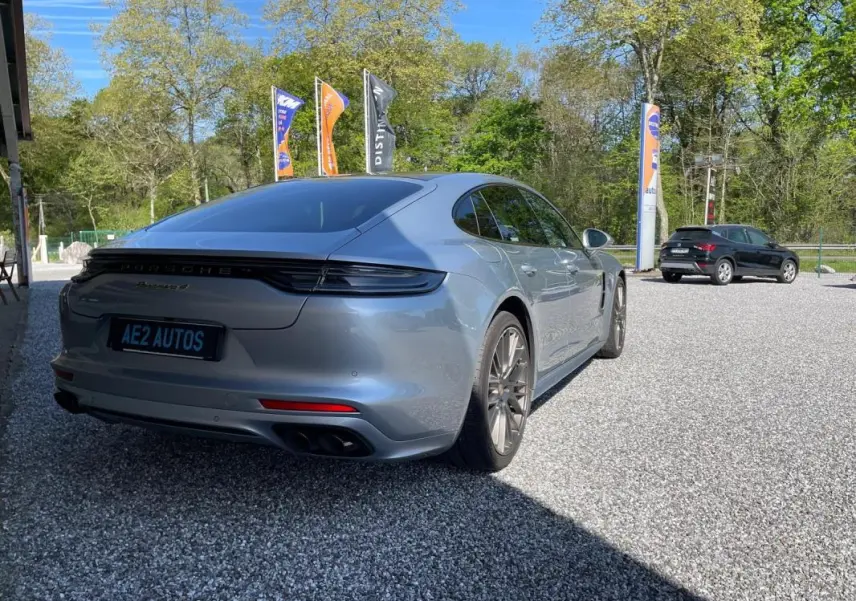 Vue 3/4 arrière droite d'une Porsche Panamera 4 V6 3.0 Hybrid gris métallisé avec feux arrière allongés et jantes sport.