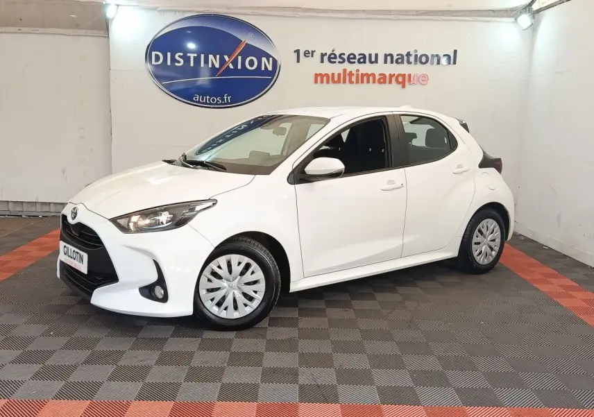 Toyota Yaris hybride blanche vue de profil avant droit dans un showroom avec logo Distinxion en arrière-plan.