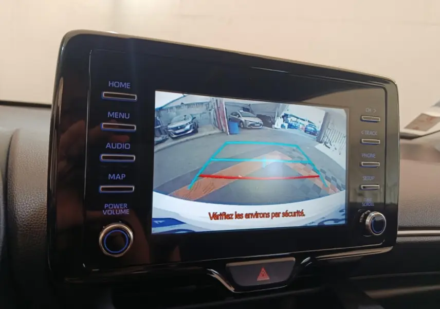Écran tactile central montrant la caméra de recul avec guidage de trajectoire dans une Toyota Yaris blanche hybride.