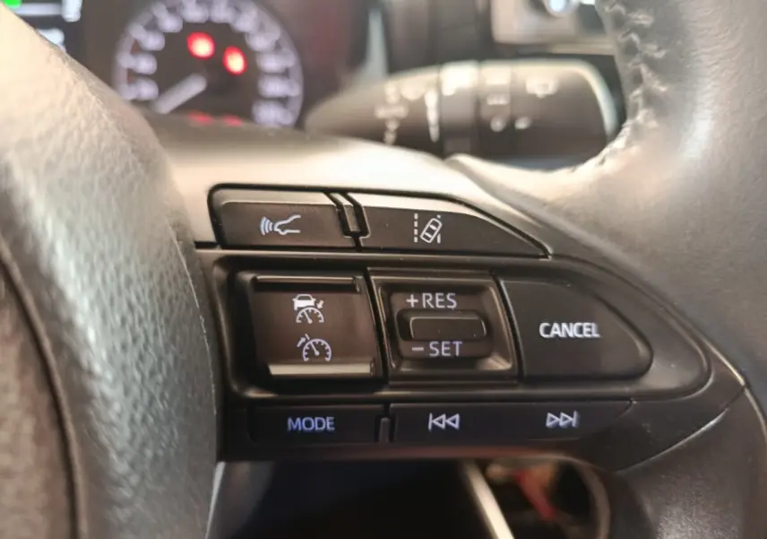 Gros plan sur les commandes du volant cuir multifonctions de la Toyota Yaris hybride 2022, boutons noirs avec symboles blancs.