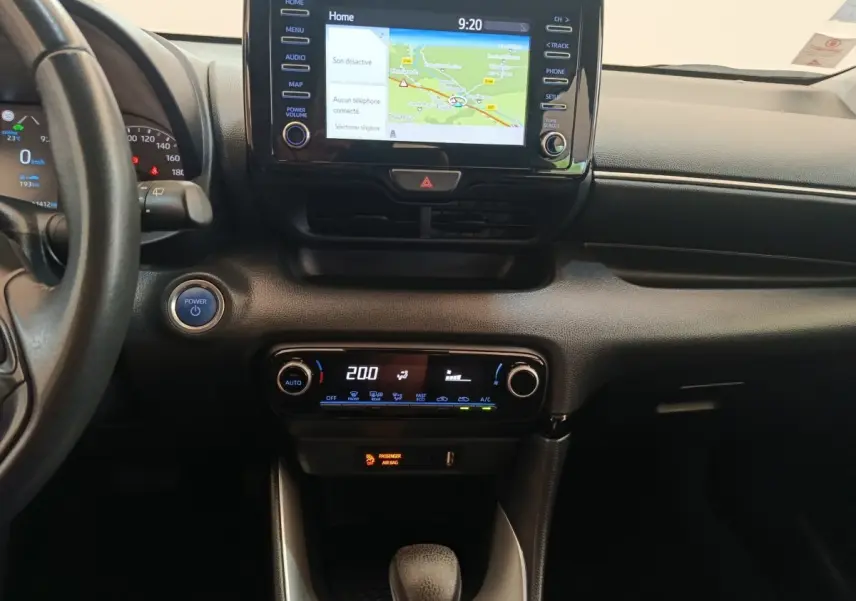 Vue intérieure centrée sur la console centrale de la Toyota Yaris hybride 2022 avec écran tactile et commandes climatisation.