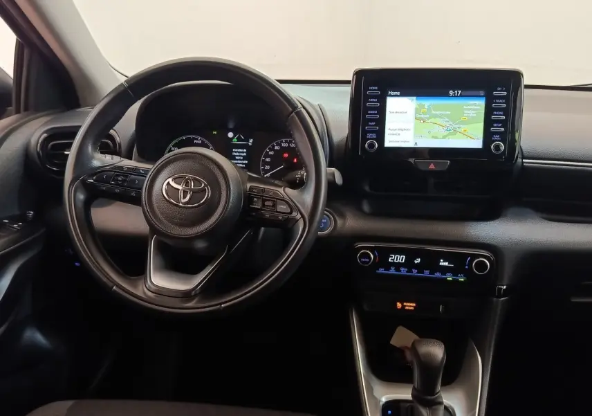 Vue intérieure centrée sur le volant cuir multifonctions et l’écran tactile du tableau de bord de la Toyota Yaris hybride 2022.