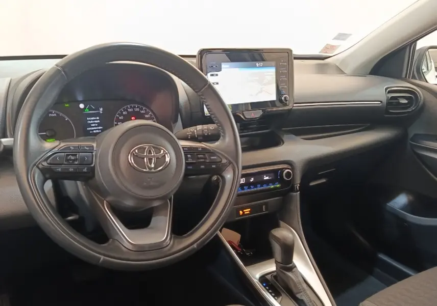 Vue intérieure avant de la Toyota Yaris hybride blanche 2022, volant cuir multifonctions et écran tactile de navigation.