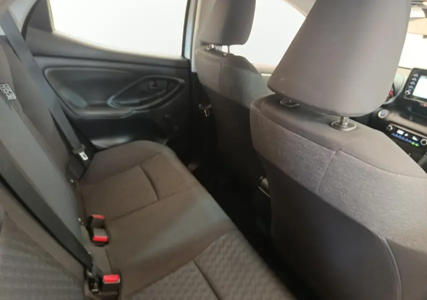 Vue intérieure arrière côté gauche de la Toyota Yaris hybride 2022 avec sièges tissu gris foncé et ceintures de sécurité.