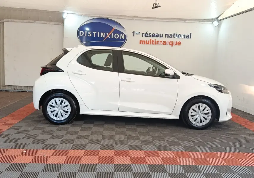 Profil droit de la Toyota Yaris hybride blanche 2022, avec jantes pleines et toit noir contrastant visible en arrière-plan.