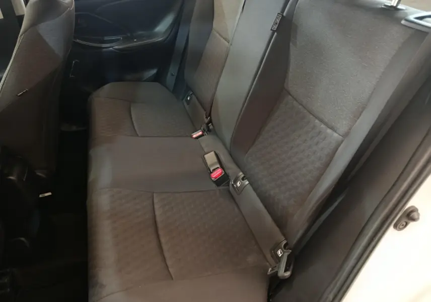 Vue côté droit de la banquette arrière noire de la Toyota Yaris hybride blanche 2022 avec ceintures et appuie-têtes visibles.
