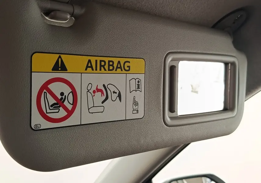 Détail du pare-soleil côté conducteur de la Toyota Yaris blanche 2022 avec miroir et avertissement airbag visible.