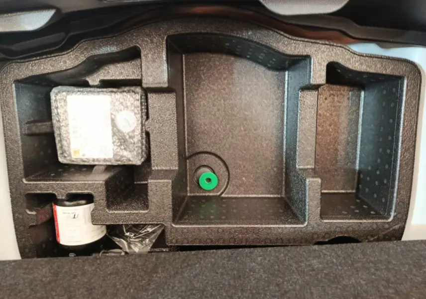 Rangement en mousse noire dans le coffre d'une Toyota Yaris hybride blanche, vue de dessus, sans objets visibles.