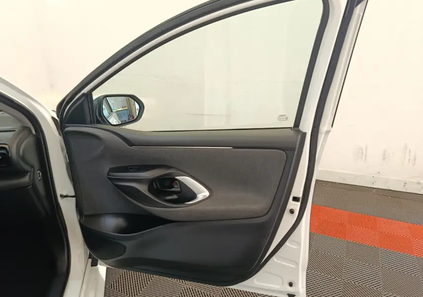 Vue intérieure de la porte arrière droite blanche d'une Toyota Yaris Hybride 2022, avec garniture grise et poignée noire.