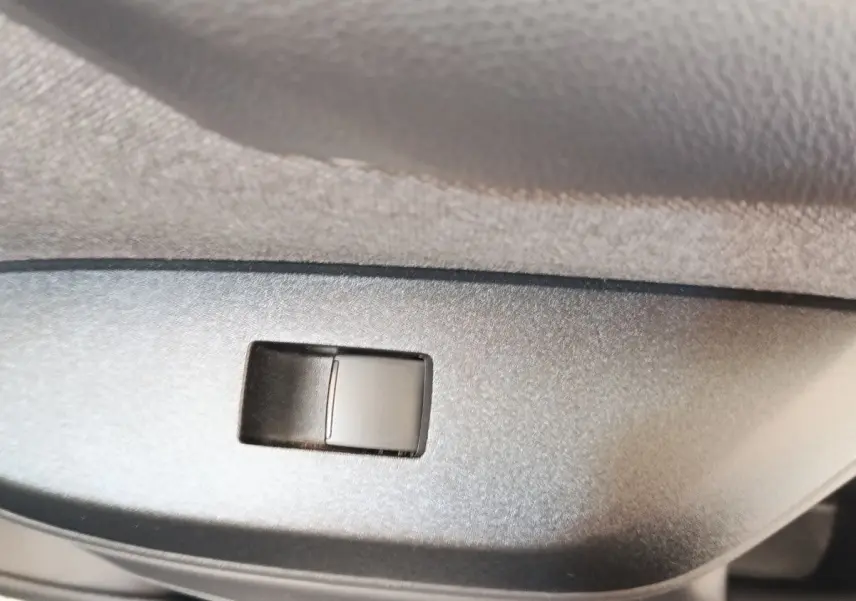 Gros plan sur le bouton de réglage du siège côté conducteur dans l’habitacle de la Toyota Yaris blanche hybride 2022.